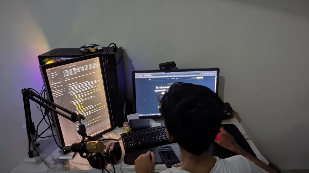 Muhammad Usman Ashraf at his development workspace with vertical code monitor and dual display setup.